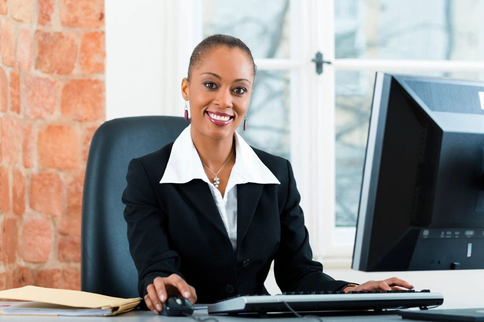 A woman sitting at her desk in front of two computers.